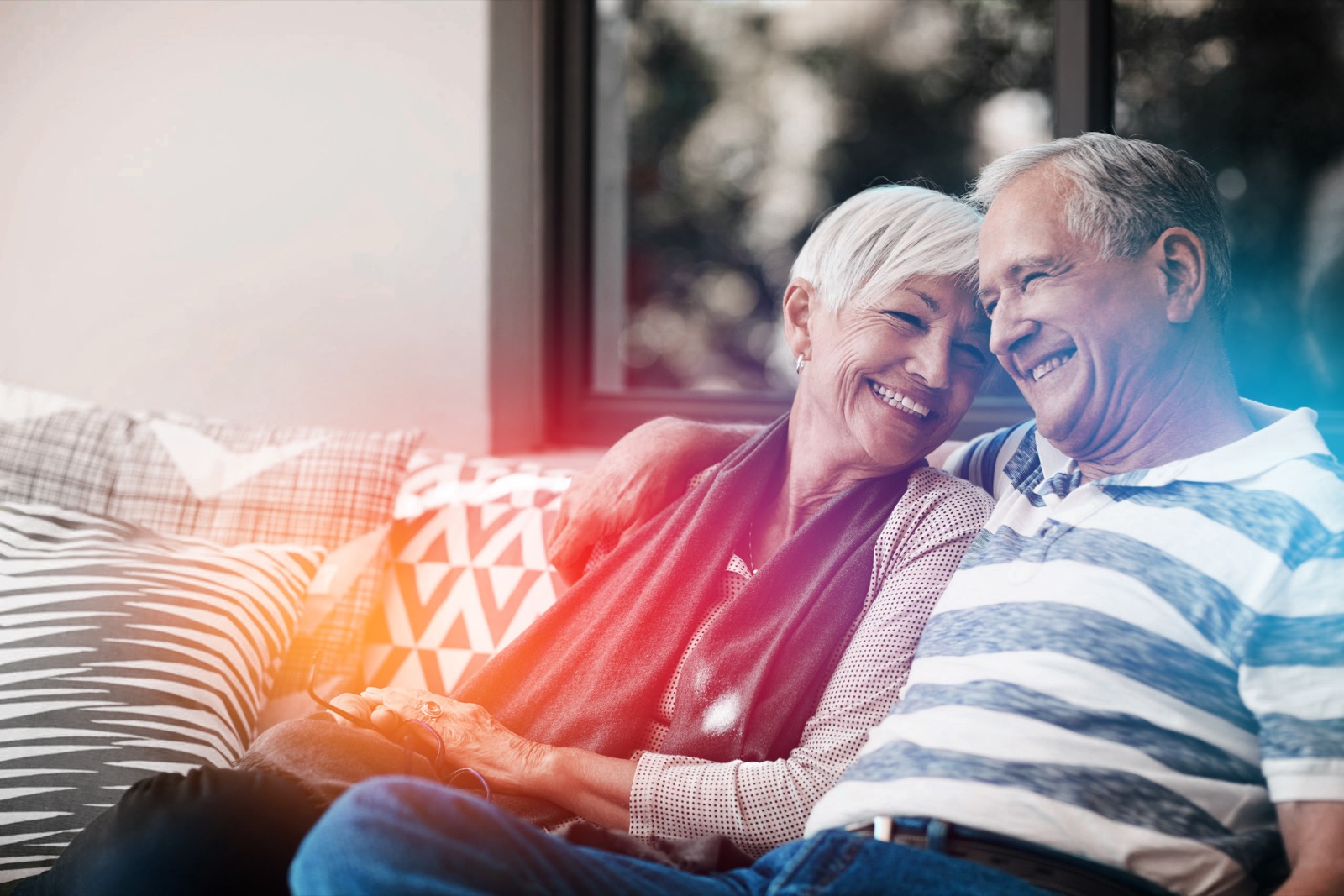 Couple laughing together on a couch with warm prismatic light
