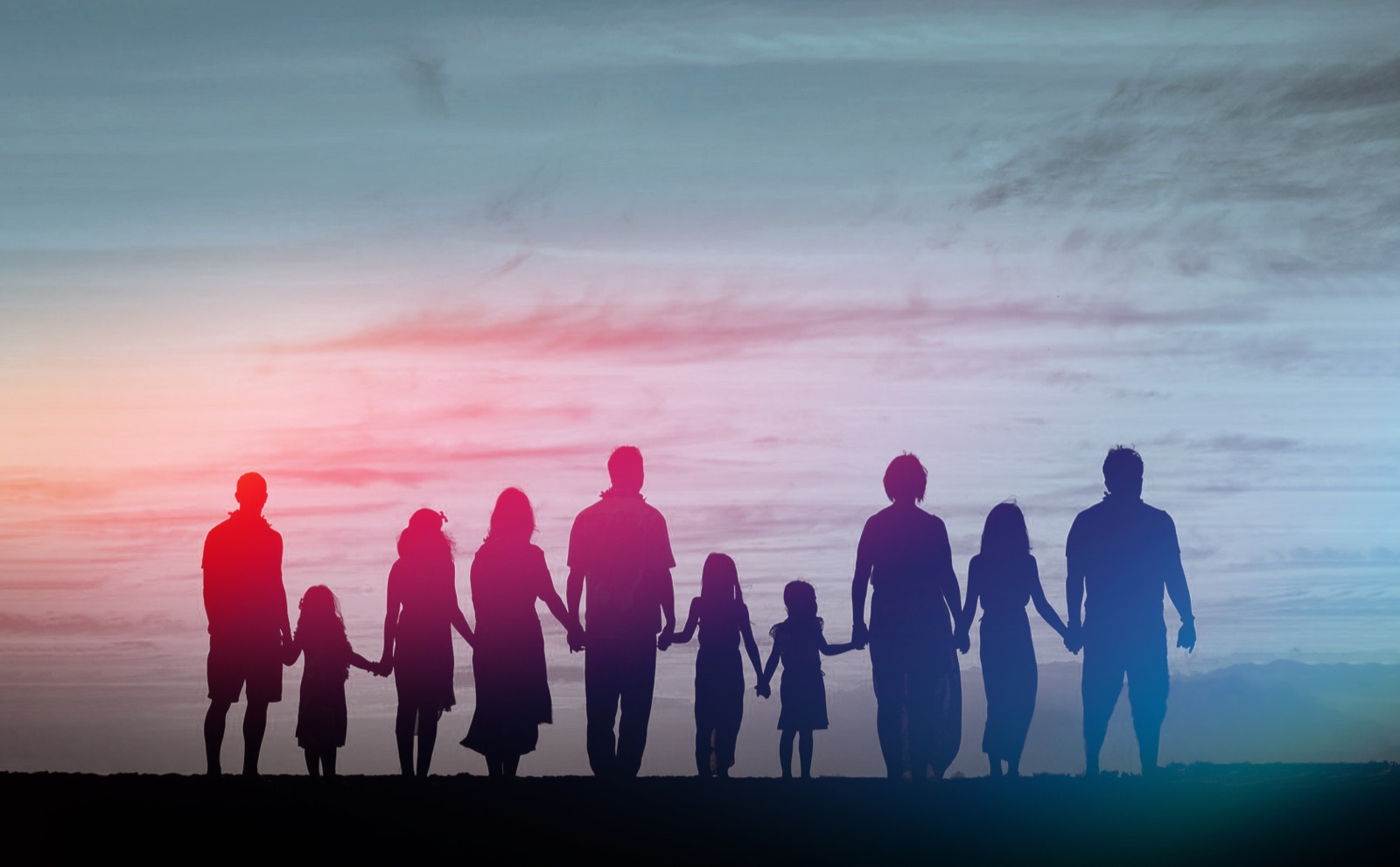 Multi-generational family silhouetted against a prismatic sunset sky